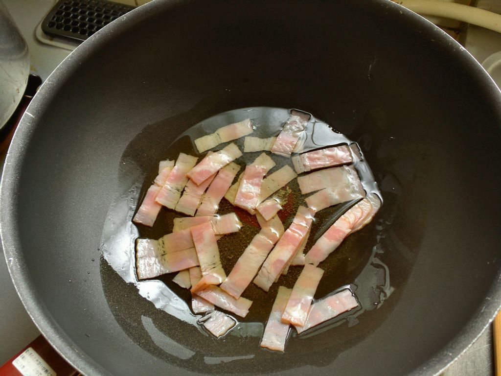 フライパンにオリーブオイルとベーコンの細切りを入れて、ごく弱火で炒めます。